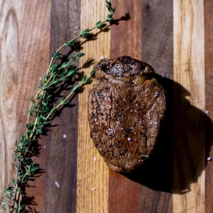 Cooked filet mignon on a cutting board with fresh thyme