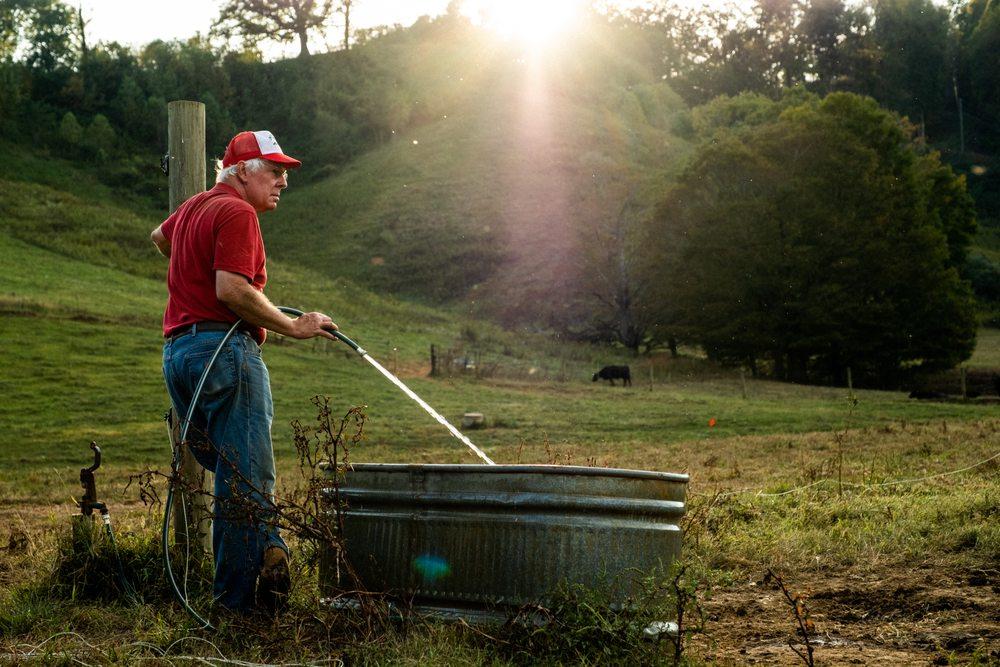 Bob Shipley filling a water trough for the cattle at sunset