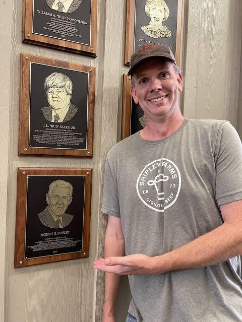 Gray Shipley standing beside R.G. Shipley's commemorative plaque at the Western NC Agricultural Hall of Fame